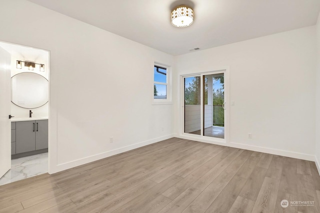 unfurnished room with sink and light hardwood / wood-style floors