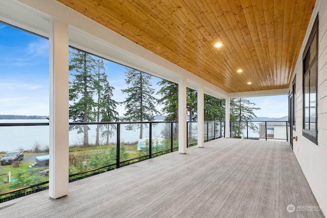 unfurnished sunroom featuring a healthy amount of sunlight, a water view, and wood ceiling