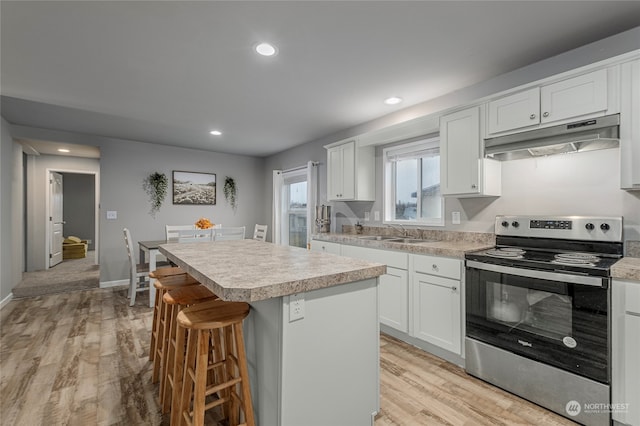 kitchen featuring light hardwood / wood-style flooring, a kitchen island, electric range, white cabinets, and sink