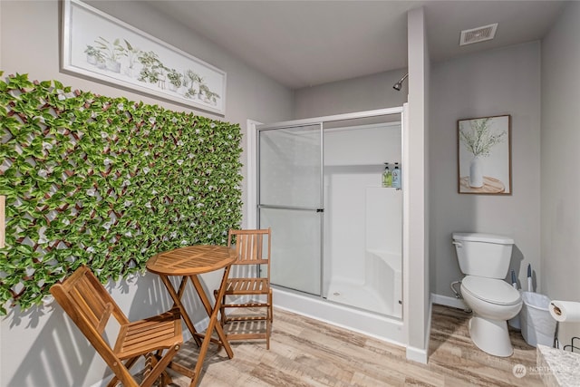 bathroom with walk in shower, toilet, and hardwood / wood-style flooring