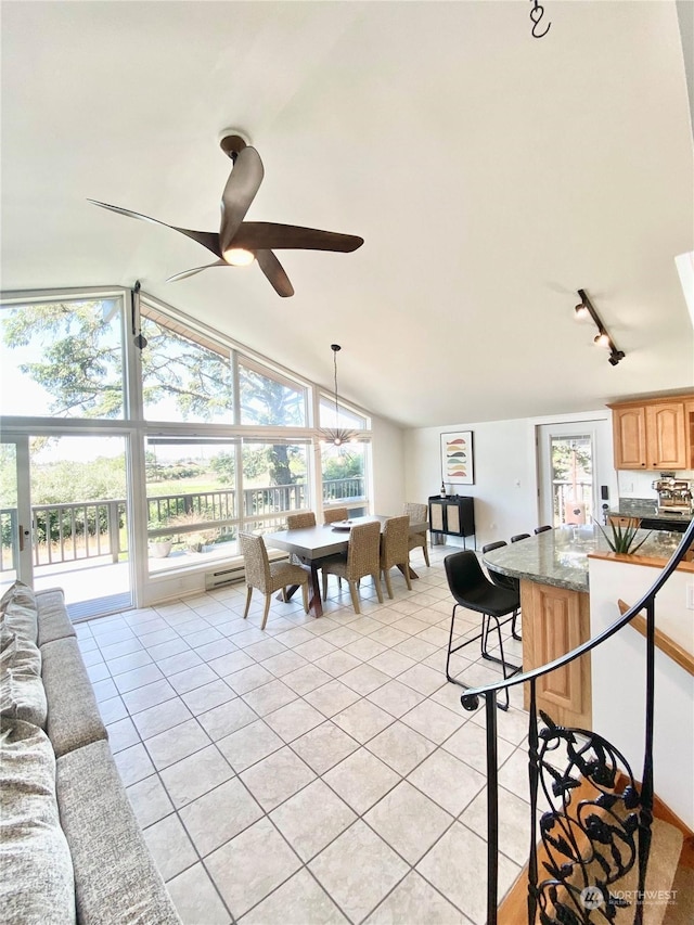 interior space with ceiling fan, plenty of natural light, light tile patterned floors, and vaulted ceiling