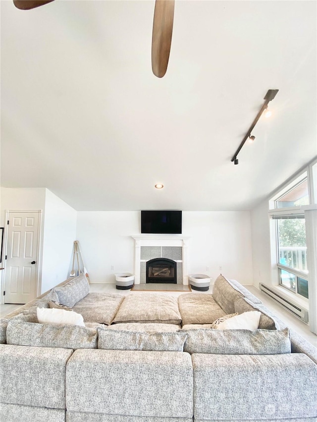 living room with a tile fireplace, ceiling fan, baseboard heating, vaulted ceiling, and track lighting