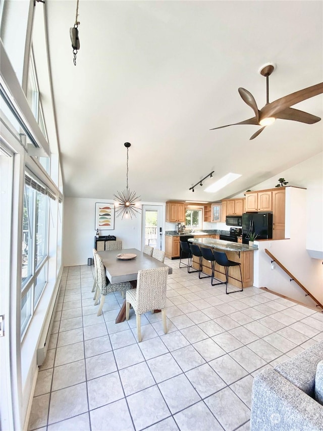 dining space with ceiling fan, light tile patterned floors, rail lighting, and vaulted ceiling