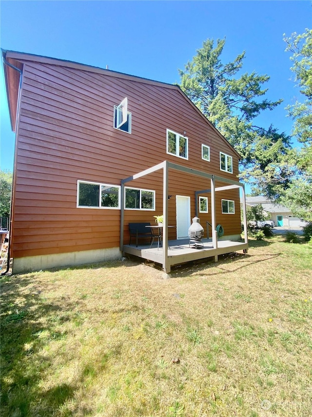 rear view of house with a deck and a lawn