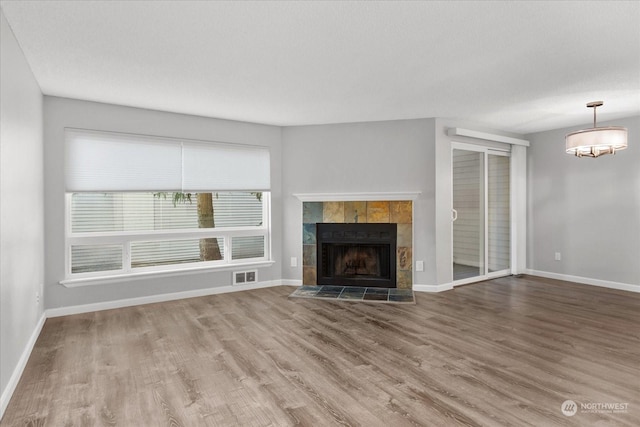 unfurnished living room with wood-type flooring and a tile fireplace