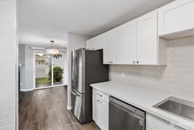 kitchen with tasteful backsplash, stainless steel appliances, hardwood / wood-style flooring, and white cabinets