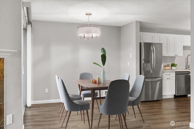 dining space with dark wood-type flooring, sink, and a textured ceiling