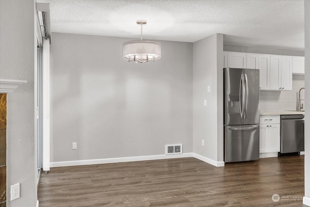 kitchen featuring white cabinetry, stainless steel appliances, decorative light fixtures, and dark hardwood / wood-style flooring