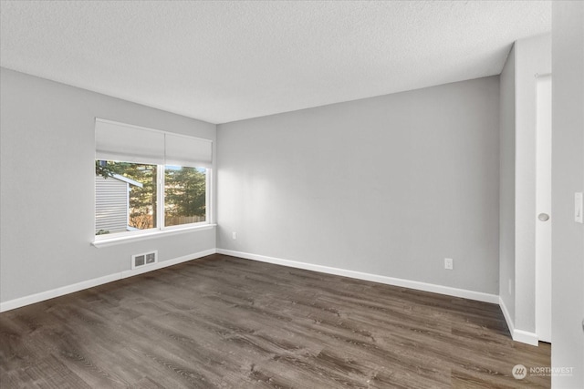 unfurnished room featuring dark wood-type flooring and a textured ceiling