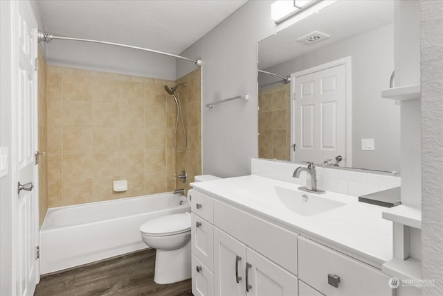 full bathroom with vanity, hardwood / wood-style flooring, toilet, and tiled shower / bath