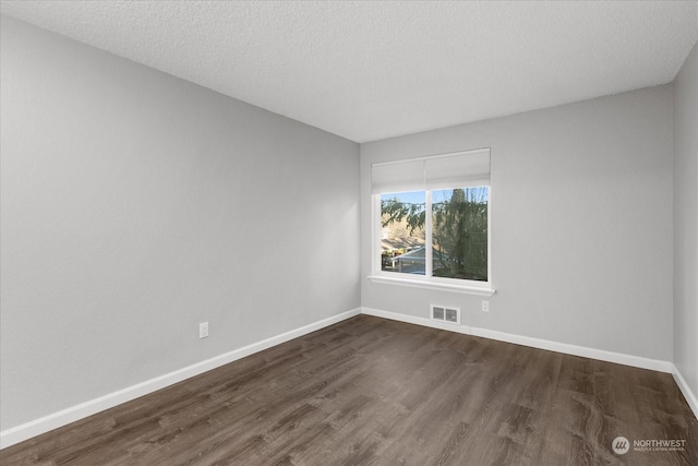 spare room featuring dark wood-type flooring and a textured ceiling