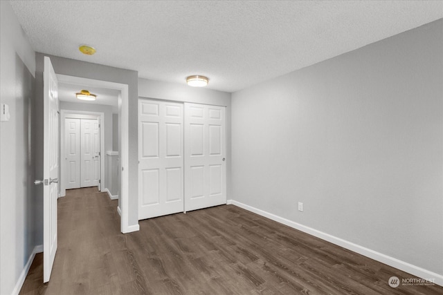 unfurnished bedroom featuring dark hardwood / wood-style floors, a textured ceiling, and a closet