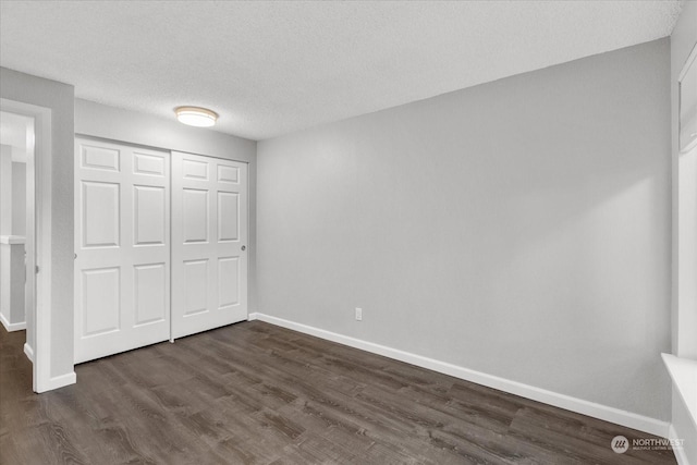 unfurnished bedroom with a textured ceiling, dark hardwood / wood-style flooring, and a closet