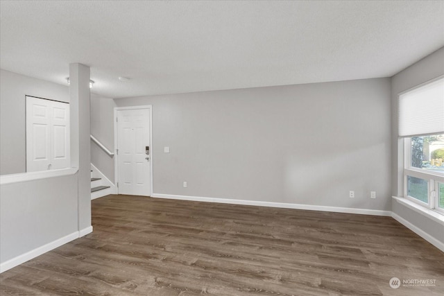 unfurnished room with dark hardwood / wood-style floors and a textured ceiling