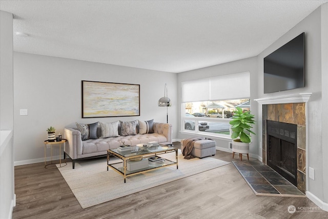 living room featuring a tiled fireplace, hardwood / wood-style flooring, and a textured ceiling