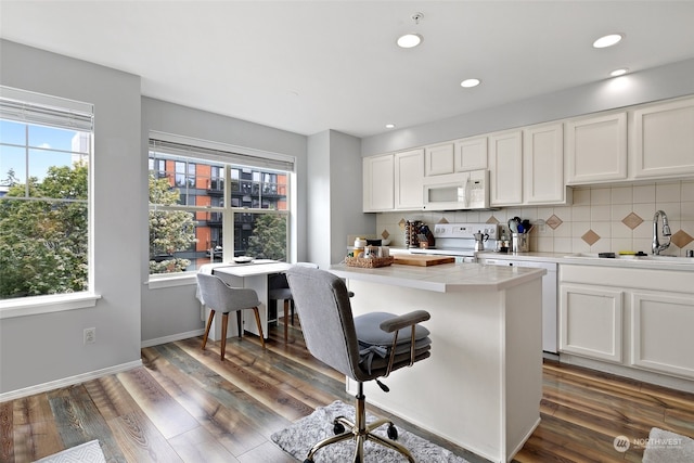 kitchen featuring white appliances, decorative backsplash, dark hardwood / wood-style flooring, white cabinetry, and sink