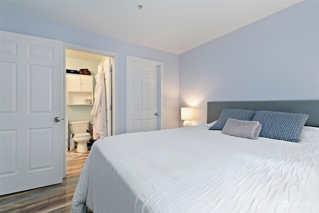 bedroom with a spacious closet, hardwood / wood-style floors, and ensuite bath