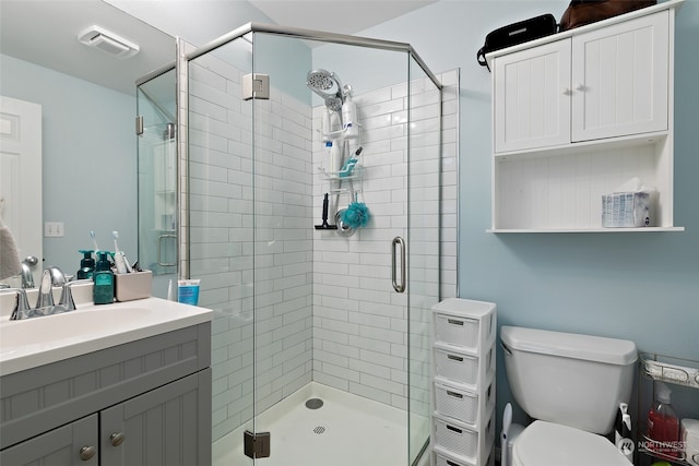 bathroom with a shower with shower door, vanity, and toilet