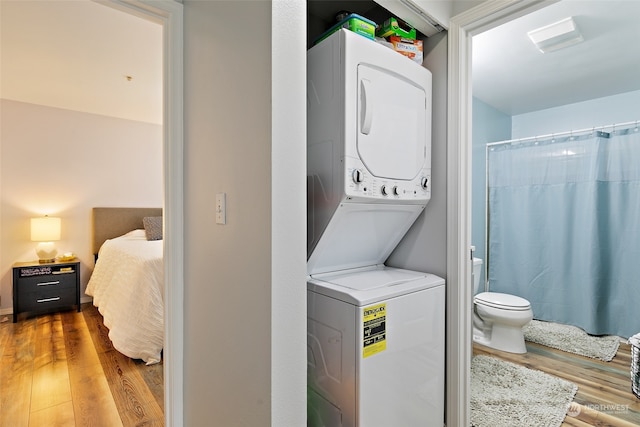 laundry area with hardwood / wood-style floors and stacked washer and dryer