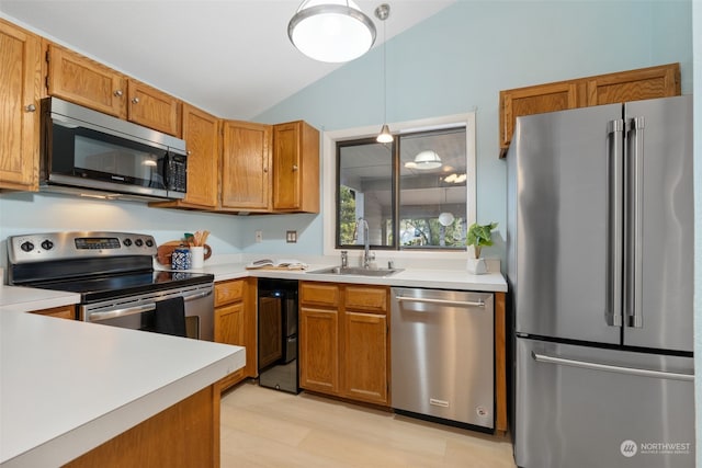 kitchen with pendant lighting, sink, stainless steel appliances, and lofted ceiling