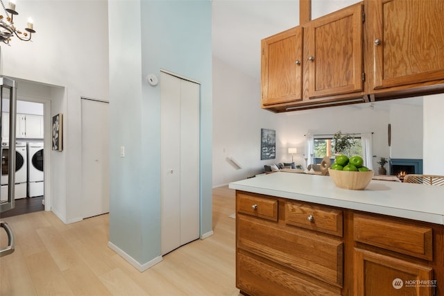 kitchen featuring separate washer and dryer, a high ceiling, a notable chandelier, and light wood-type flooring