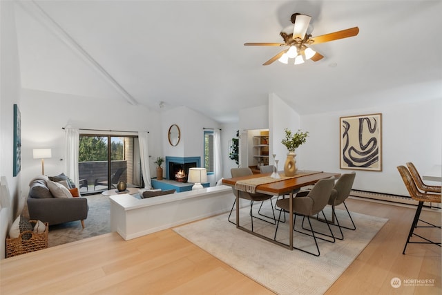 dining room with lofted ceiling, ceiling fan, a baseboard heating unit, and light wood-type flooring