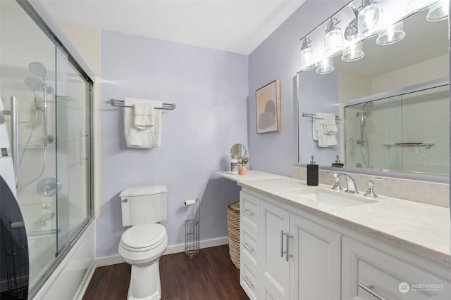 full bathroom featuring hardwood / wood-style floors, vanity, toilet, and shower / bath combination with glass door