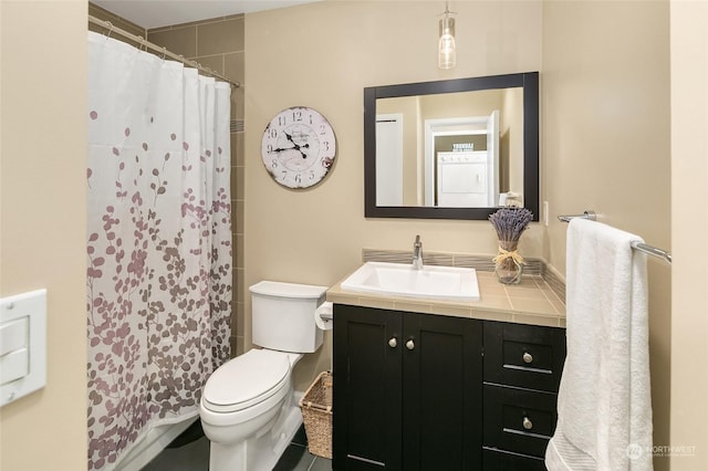 bathroom with vanity, toilet, walk in shower, and washer / clothes dryer