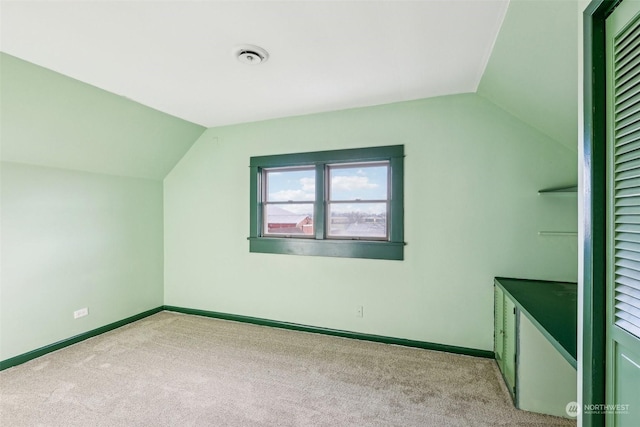 additional living space with light carpet and vaulted ceiling