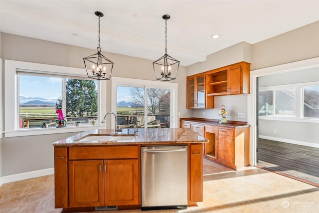 kitchen featuring light stone countertops, sink, a center island with sink, dishwasher, and a mountain view