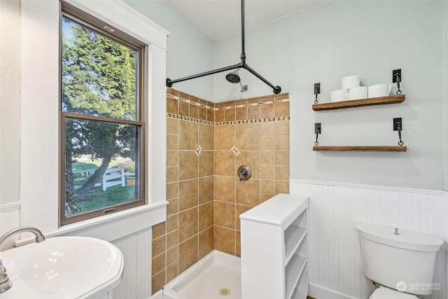 bathroom with tiled shower, toilet, and sink