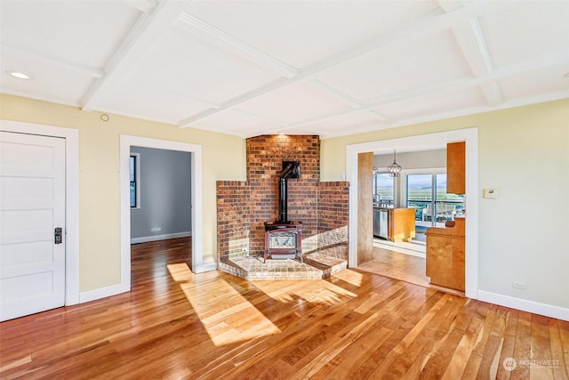 living room with beam ceiling, hardwood / wood-style flooring, a wood stove, and coffered ceiling