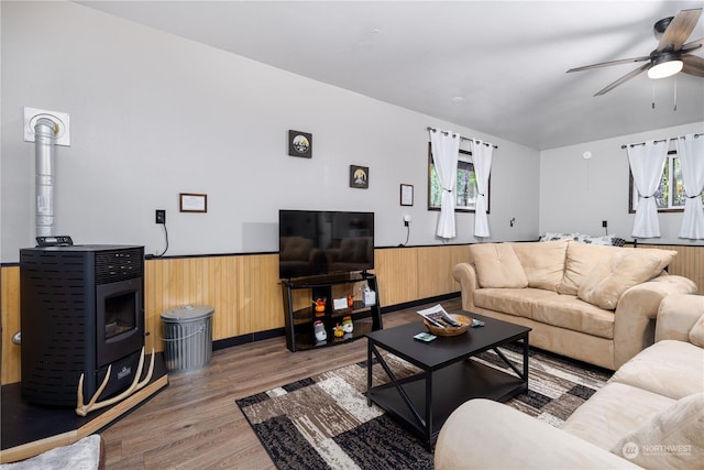 living room featuring ceiling fan, wood walls, and hardwood / wood-style flooring