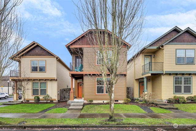 craftsman inspired home featuring a balcony and a front yard