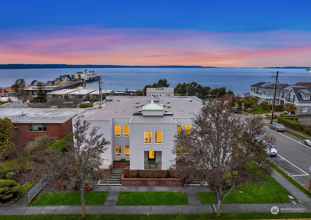 aerial view at dusk featuring a water view