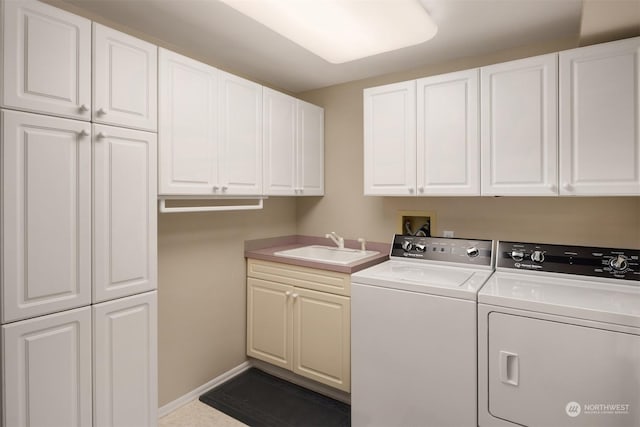 clothes washing area featuring washing machine and dryer, cabinets, and sink