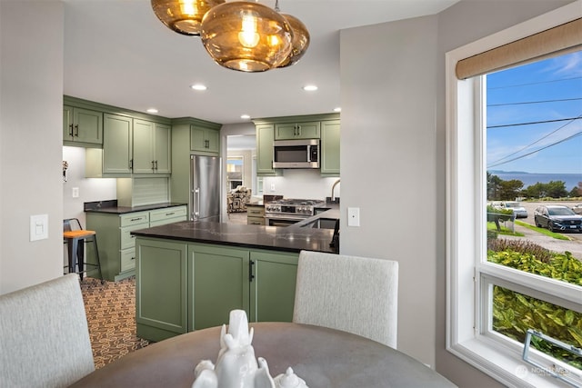 kitchen with high quality appliances, green cabinetry, pendant lighting, and plenty of natural light