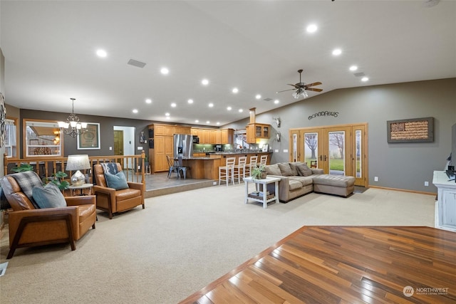 living room with french doors, ceiling fan with notable chandelier, light colored carpet, and lofted ceiling