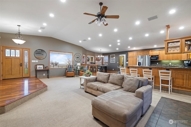 carpeted living room with ceiling fan with notable chandelier and lofted ceiling