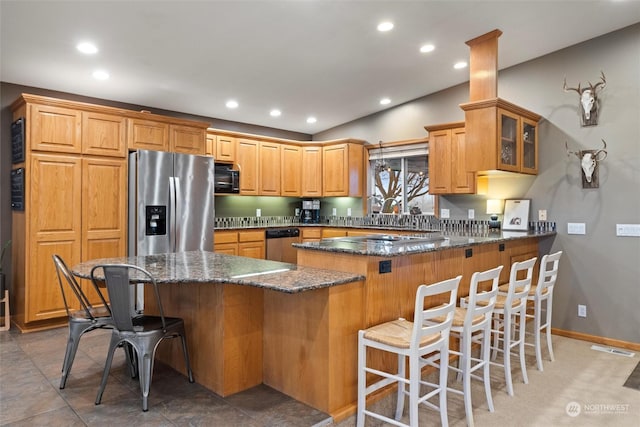 kitchen featuring a center island, dark stone countertops, lofted ceiling, a breakfast bar area, and appliances with stainless steel finishes