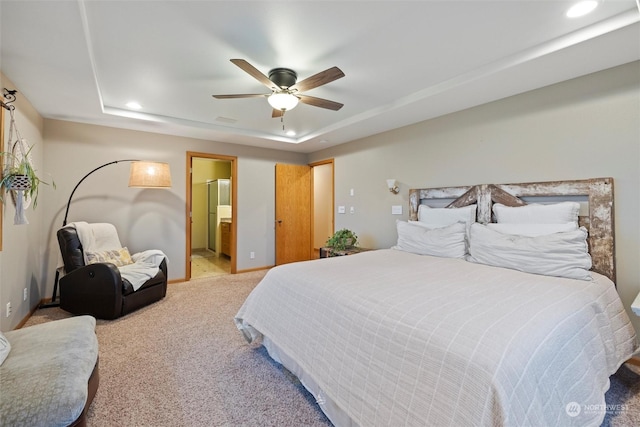 bedroom featuring carpet flooring, ceiling fan, connected bathroom, and a tray ceiling