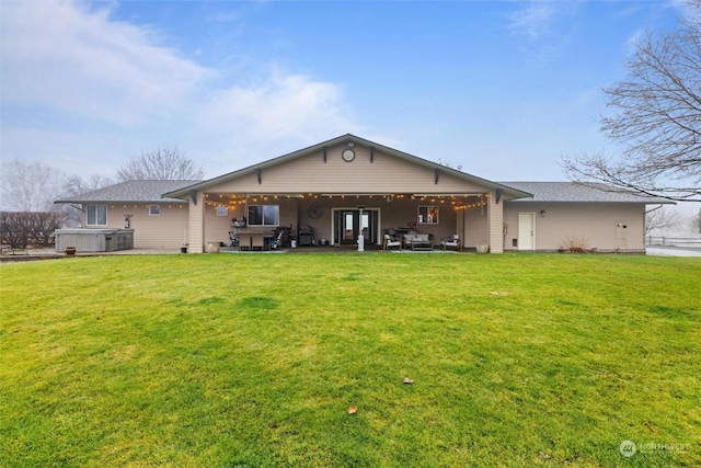 back of house with a patio, a hot tub, and a lawn