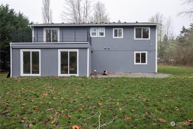 rear view of property with a balcony and a lawn