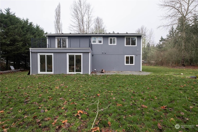 rear view of property featuring a lawn and a balcony