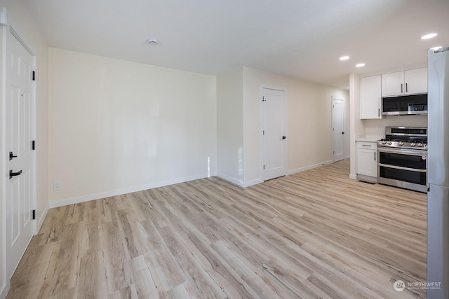 kitchen featuring appliances with stainless steel finishes, light hardwood / wood-style flooring, and white cabinetry