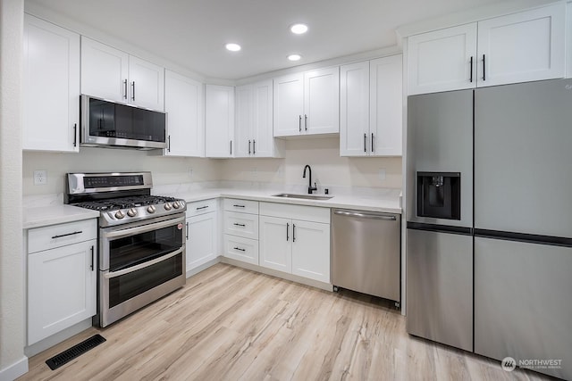 kitchen featuring light hardwood / wood-style flooring, stainless steel appliances, white cabinetry, and sink