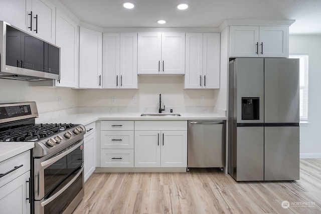 kitchen featuring light hardwood / wood-style floors, sink, white cabinetry, and stainless steel appliances