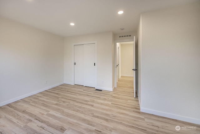 unfurnished bedroom with a closet and light hardwood / wood-style flooring