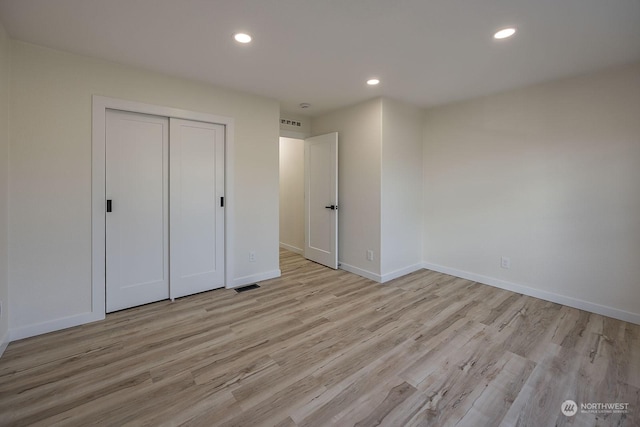 unfurnished bedroom with light hardwood / wood-style flooring and a closet