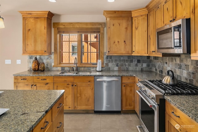 kitchen featuring sink, stainless steel appliances, dark stone counters, and backsplash